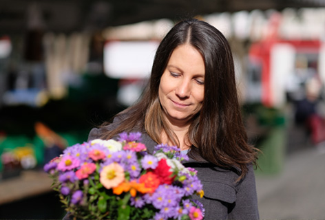 Irene Aeppli blickt auf einen bunten Blumenstrauss vor sich - n c ag