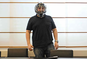 Manuel Ginesta stands in the meeting room, wears a field hockey mask and looks into the camera - n c ag
